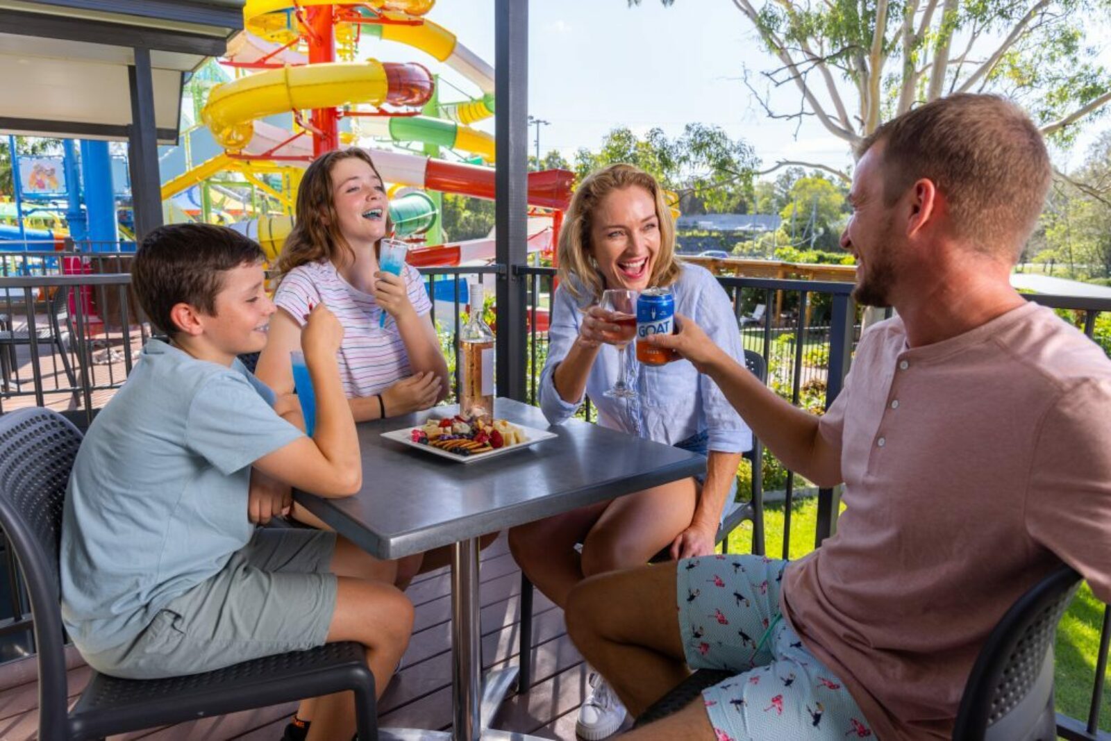 A family enjoying food and drink on a balcony overlooking the Gold Coast Holiday Park water slides